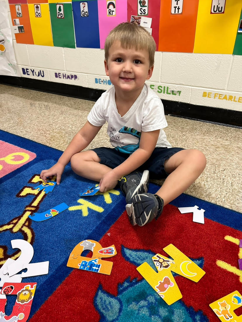 boy on carpet with alphabet letters